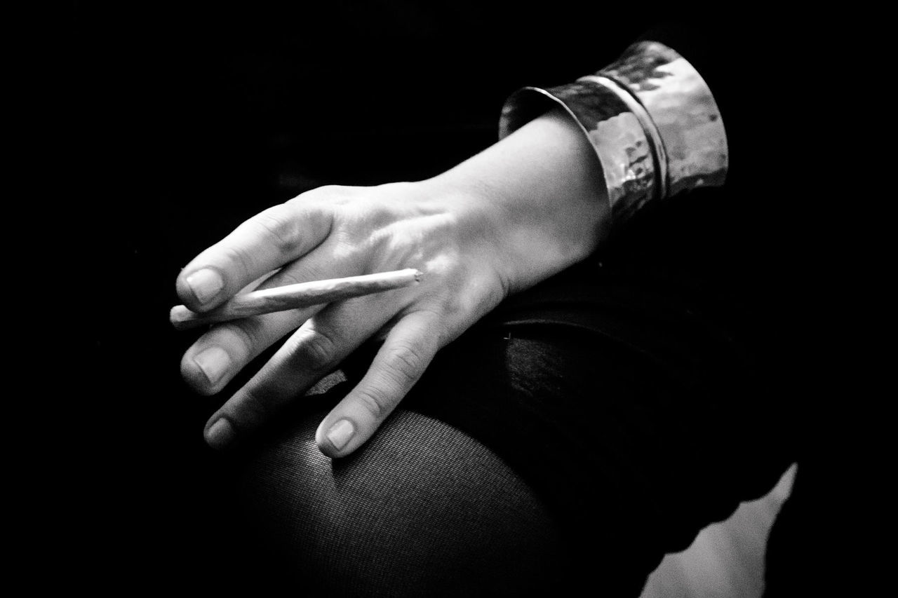 MIDSECTION OF WOMAN HOLDING HANDS AGAINST BLACK BACKGROUND