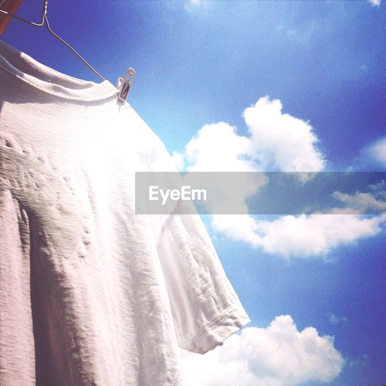 Low angle view of t-shirt hanging on clothesline against sky