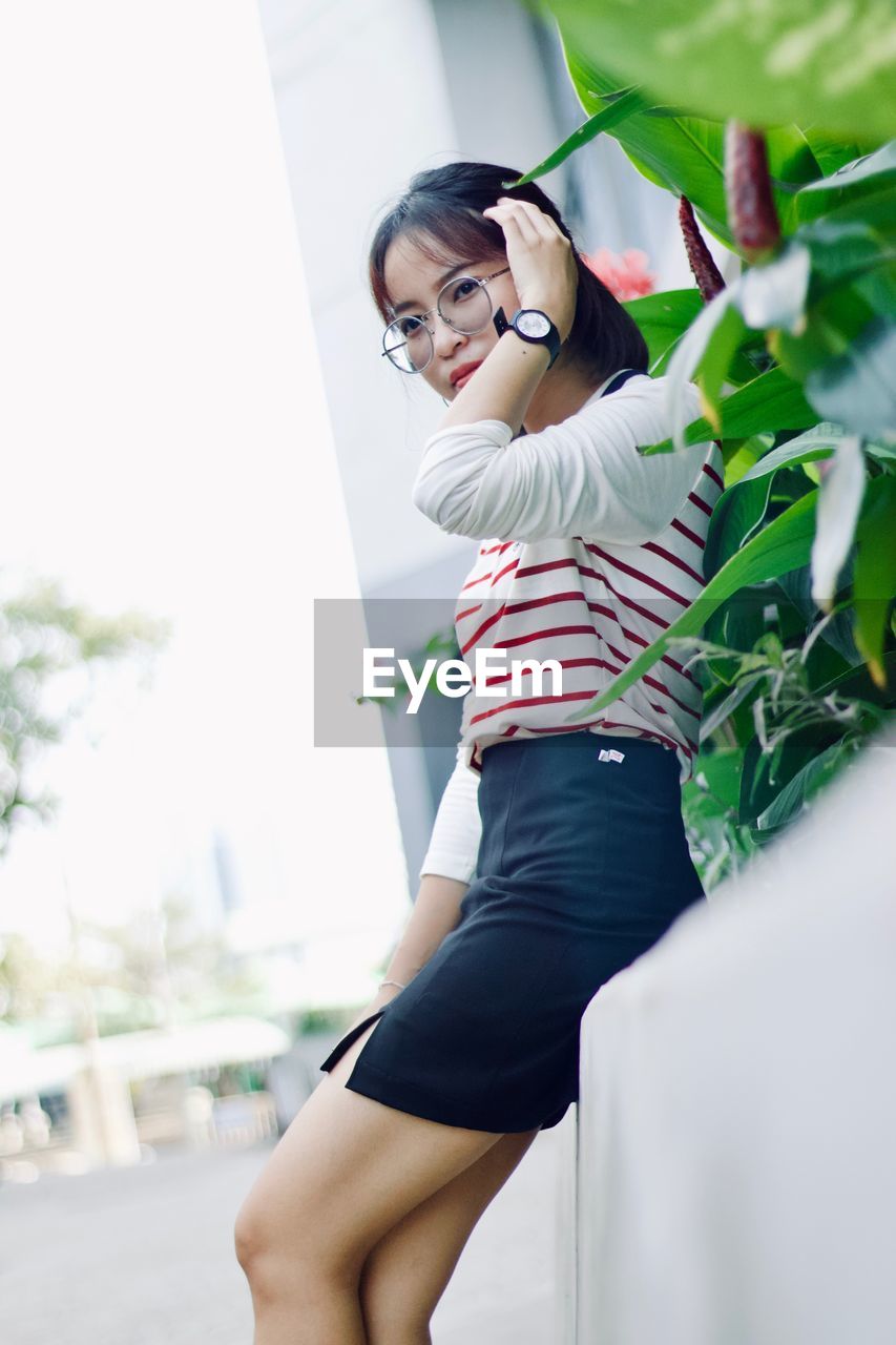 Portrait of young woman standing against plants