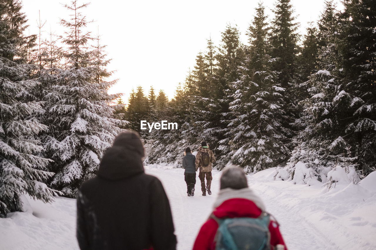 People on snow covered land against sky