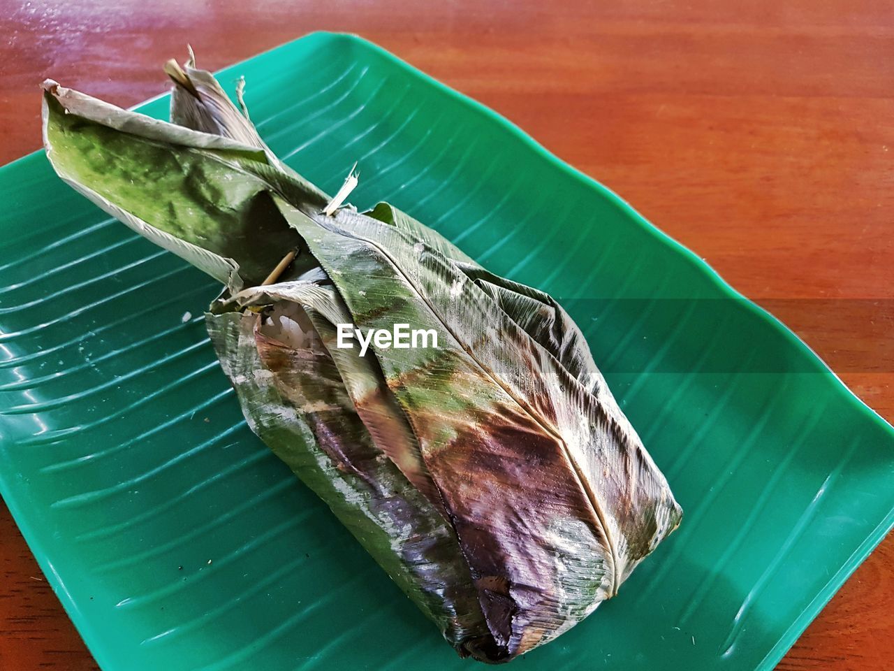 HIGH ANGLE VIEW OF BANANA LEAF ON CUTTING BOARD