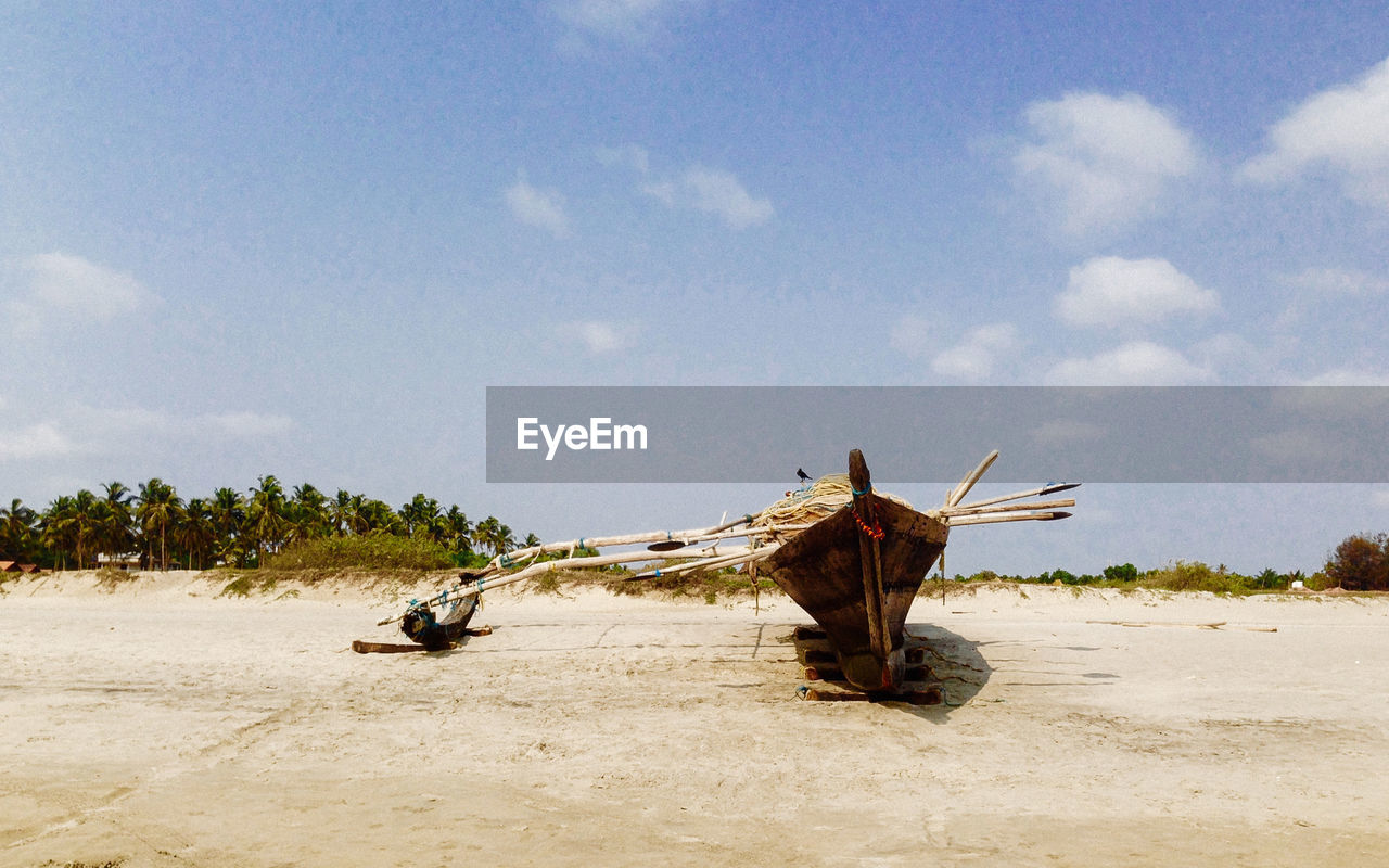 Fishing boat moored on seashore against sky