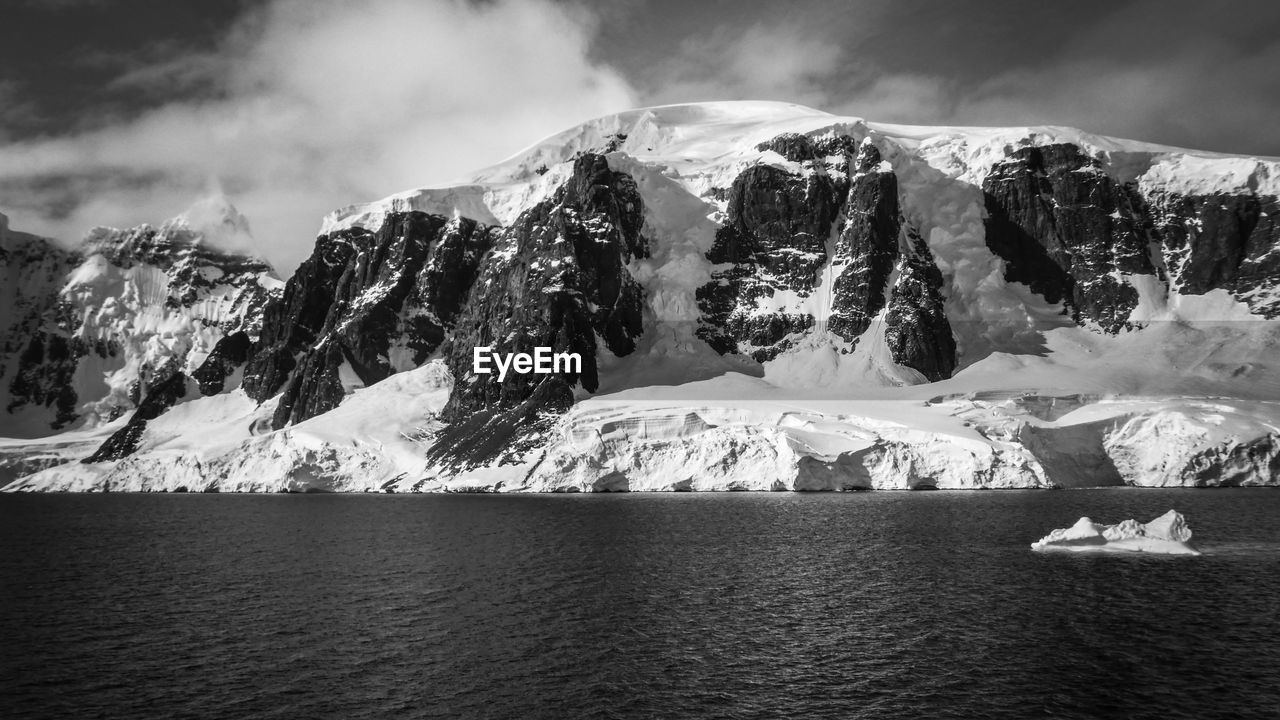 Black and white photo of glacier against snowcapped mountain in antarctica