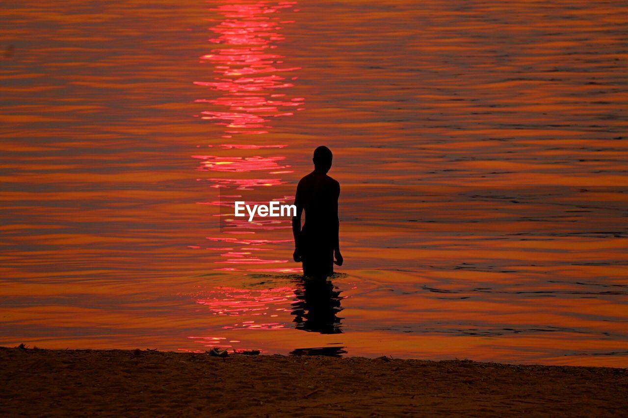 REAR VIEW OF A SILHOUETTE MAN ON ROCK