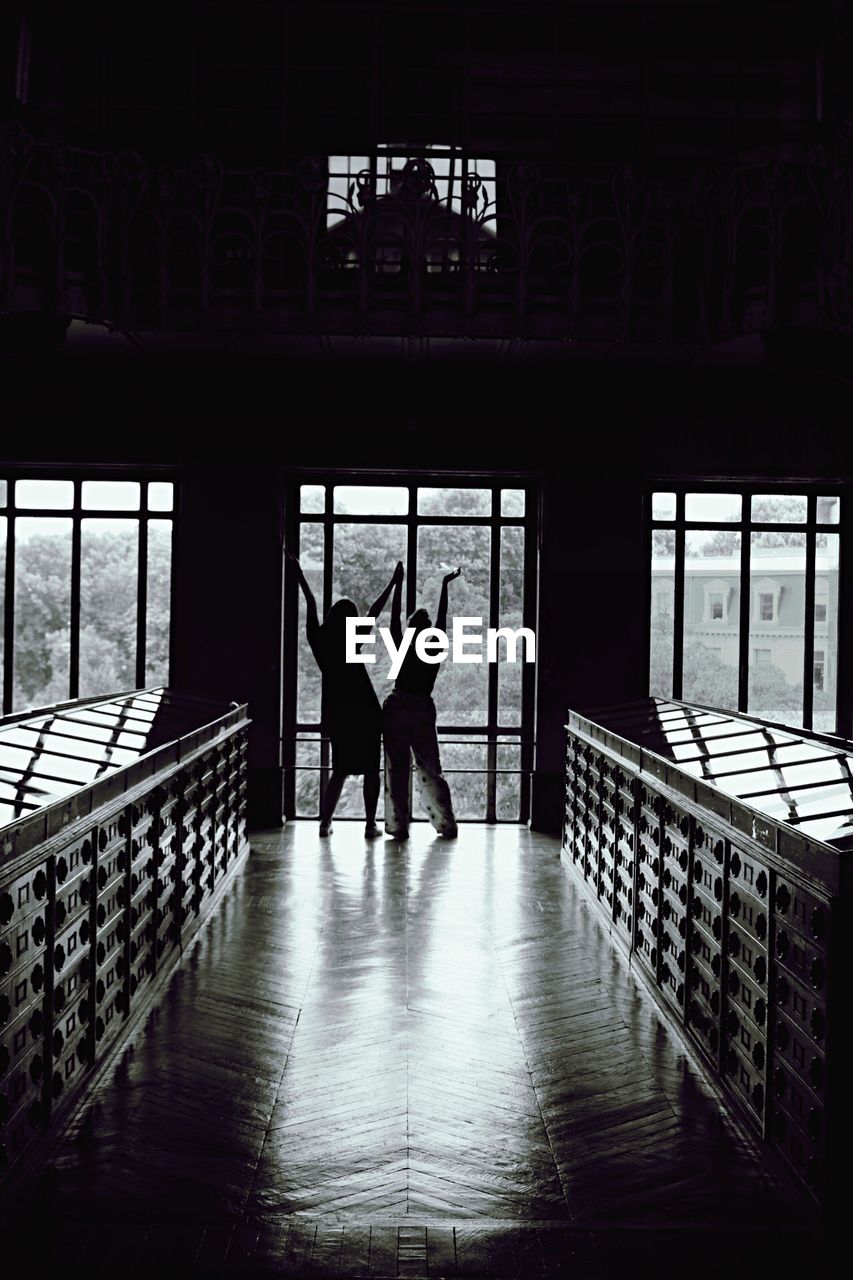 COUPLE STANDING ON RAILING WITH PEOPLE IN CORRIDOR