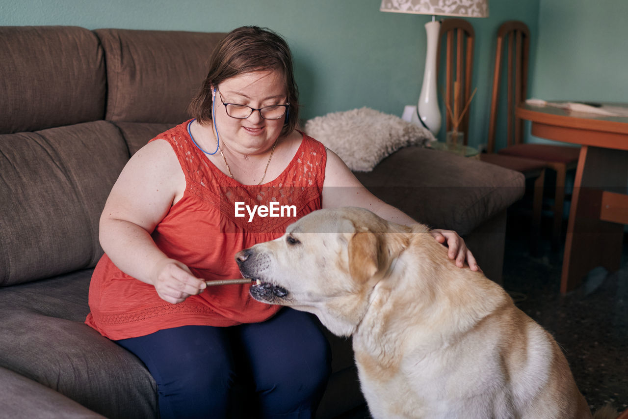 Adult woman with down syndrome has fun with her dog at home