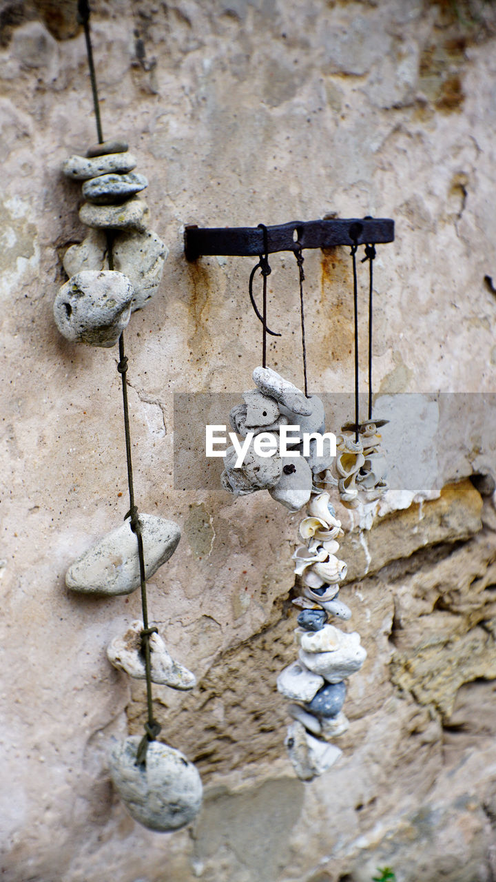 High angle view of stones hanging to rope against old wall