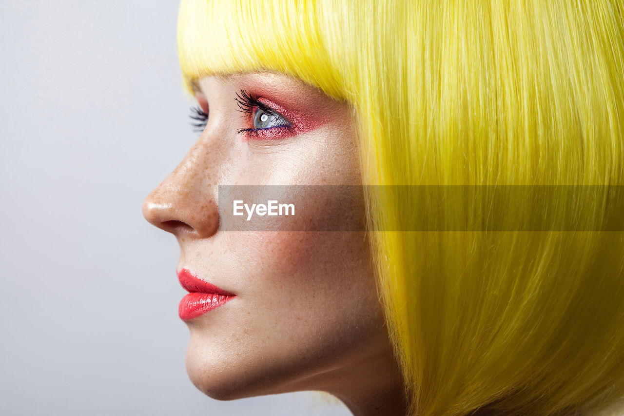 Close-up of woman looking away against white background