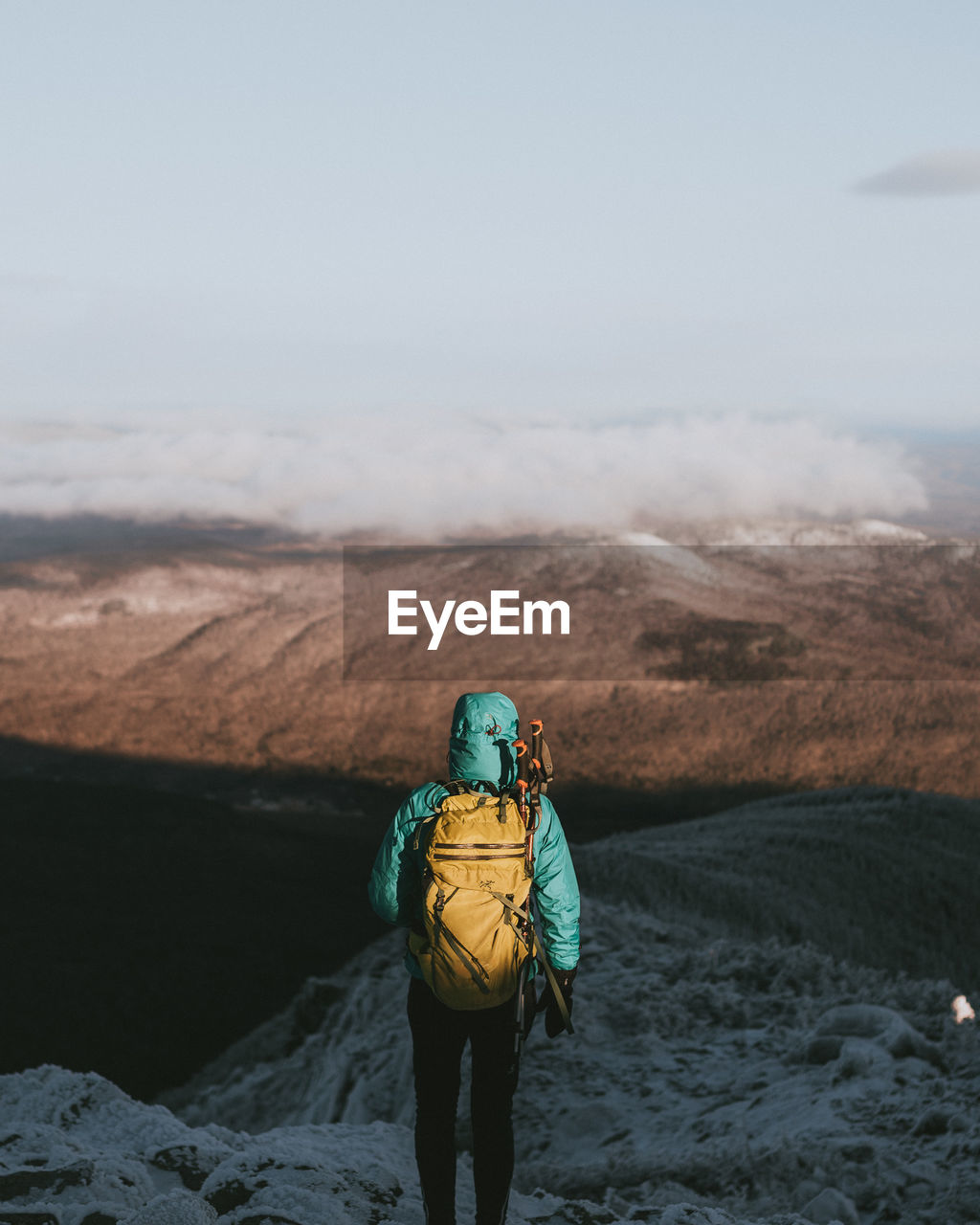 REAR VIEW OF MAN STANDING ON MOUNTAIN
