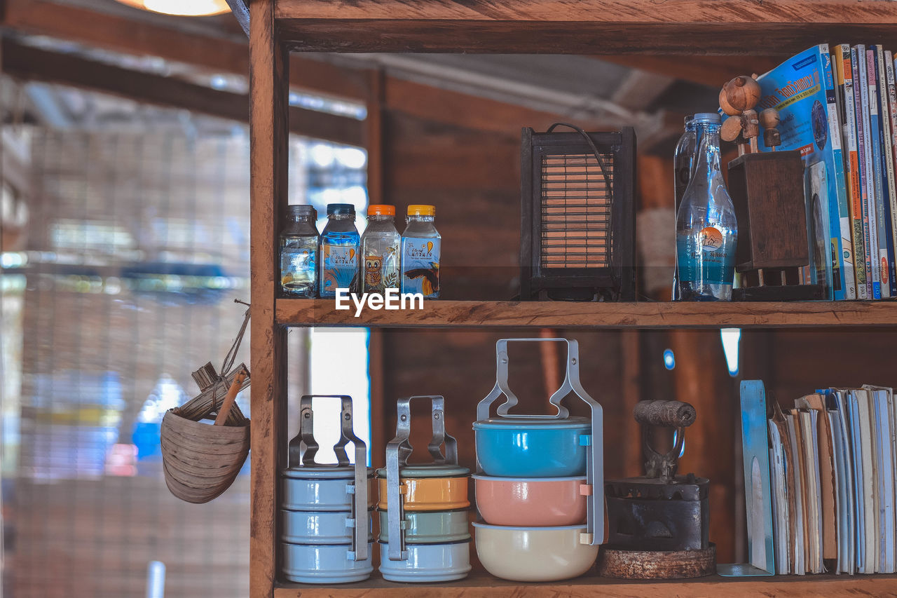 Close-up of tiffins and bottles on shelves at home