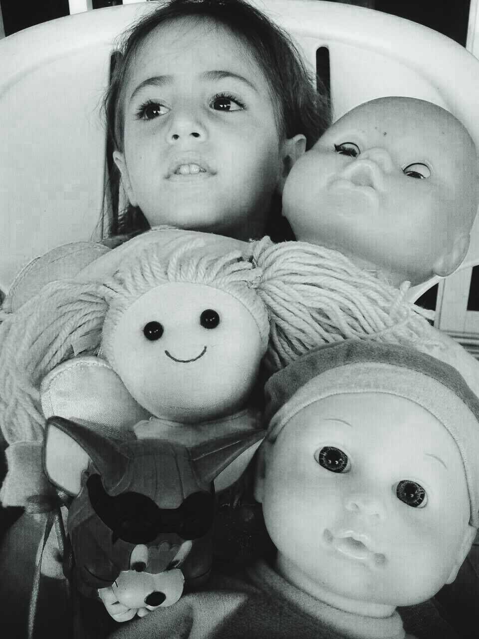 Girl with various toys sitting on chair at home