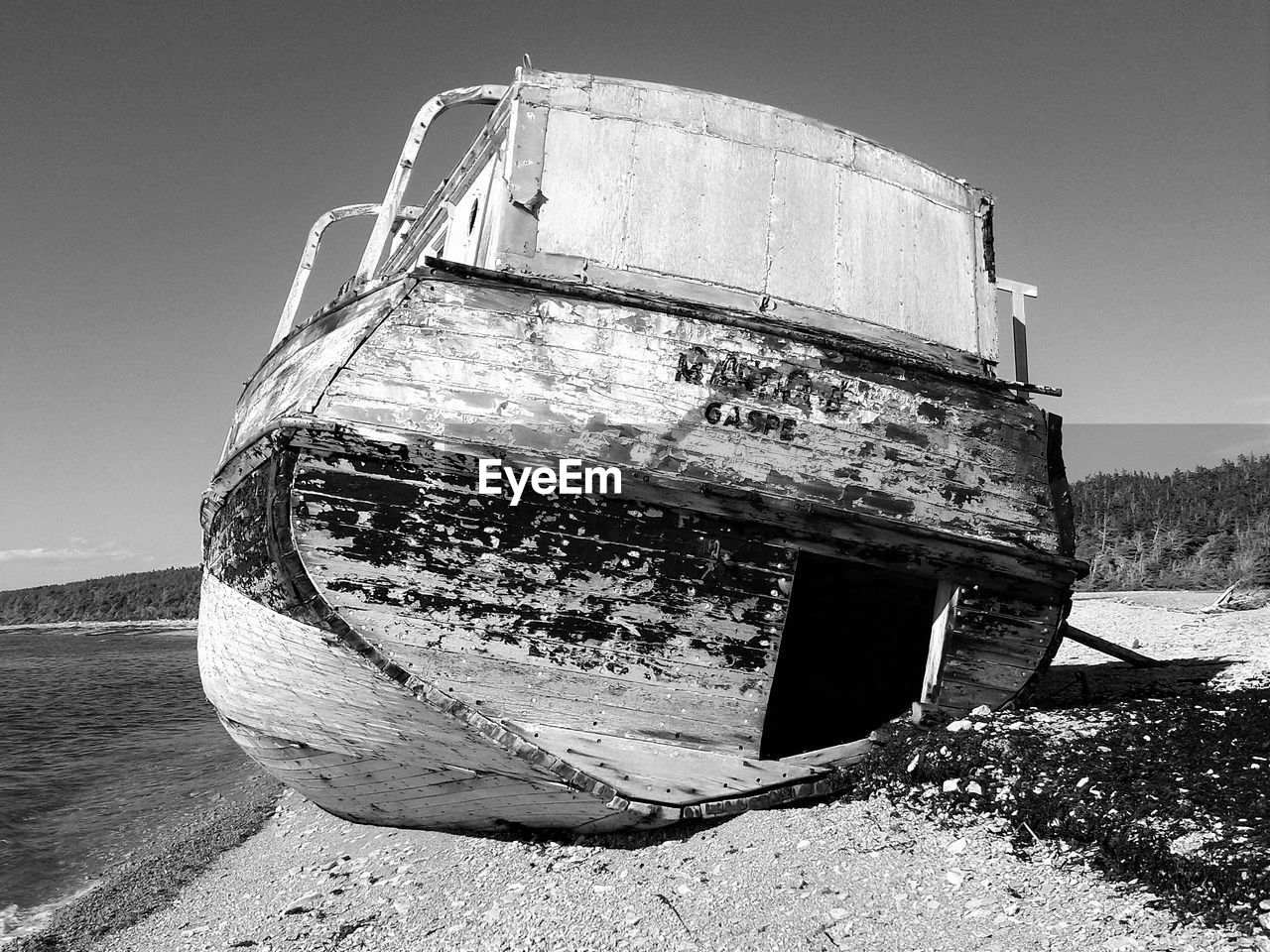 ABANDONED BOAT MOORED ON BEACH AGAINST SKY