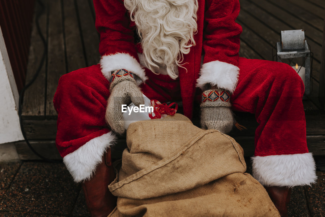 Person wearing santa costume holding christmas present