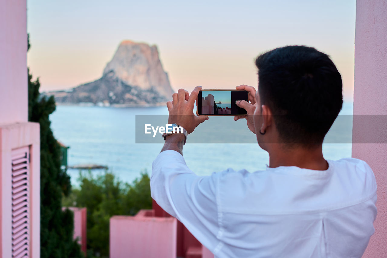 Young latin man takes a photo with his mobile