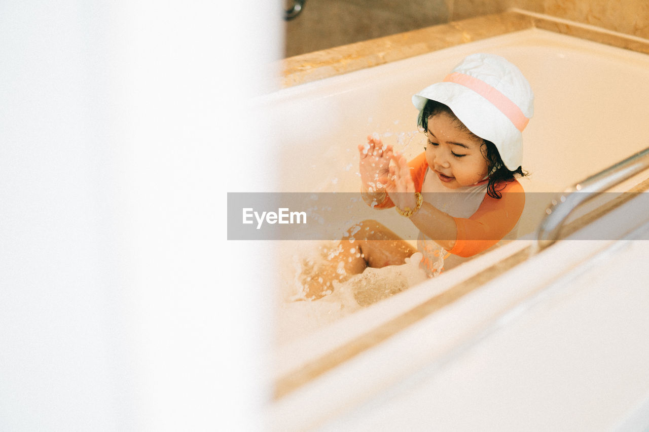 Rear view of girl playing water in bathroom