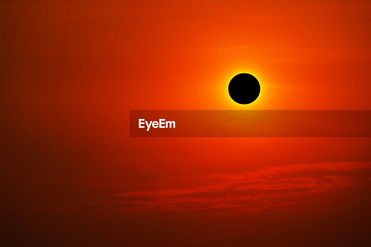 Total solar eclipse on clear red orange sky sunset in the evening