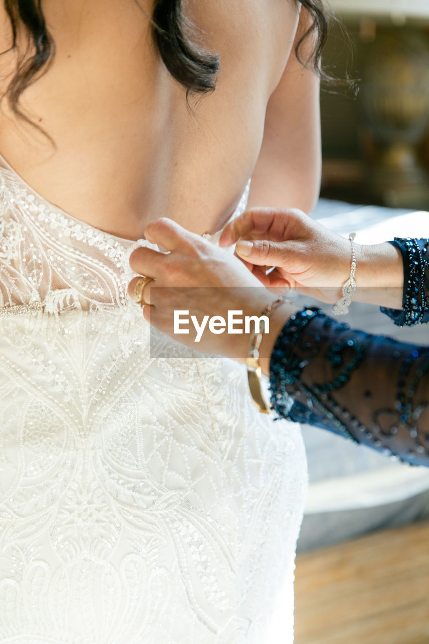 Midsection of bride holding wedding dress and getting ready 