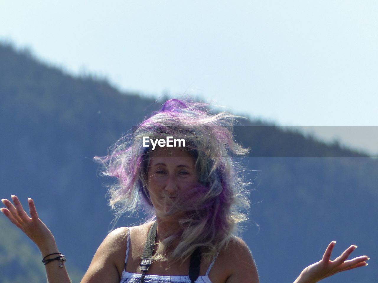 Portrait of woman with colorful hair gesturing while standing against mountain