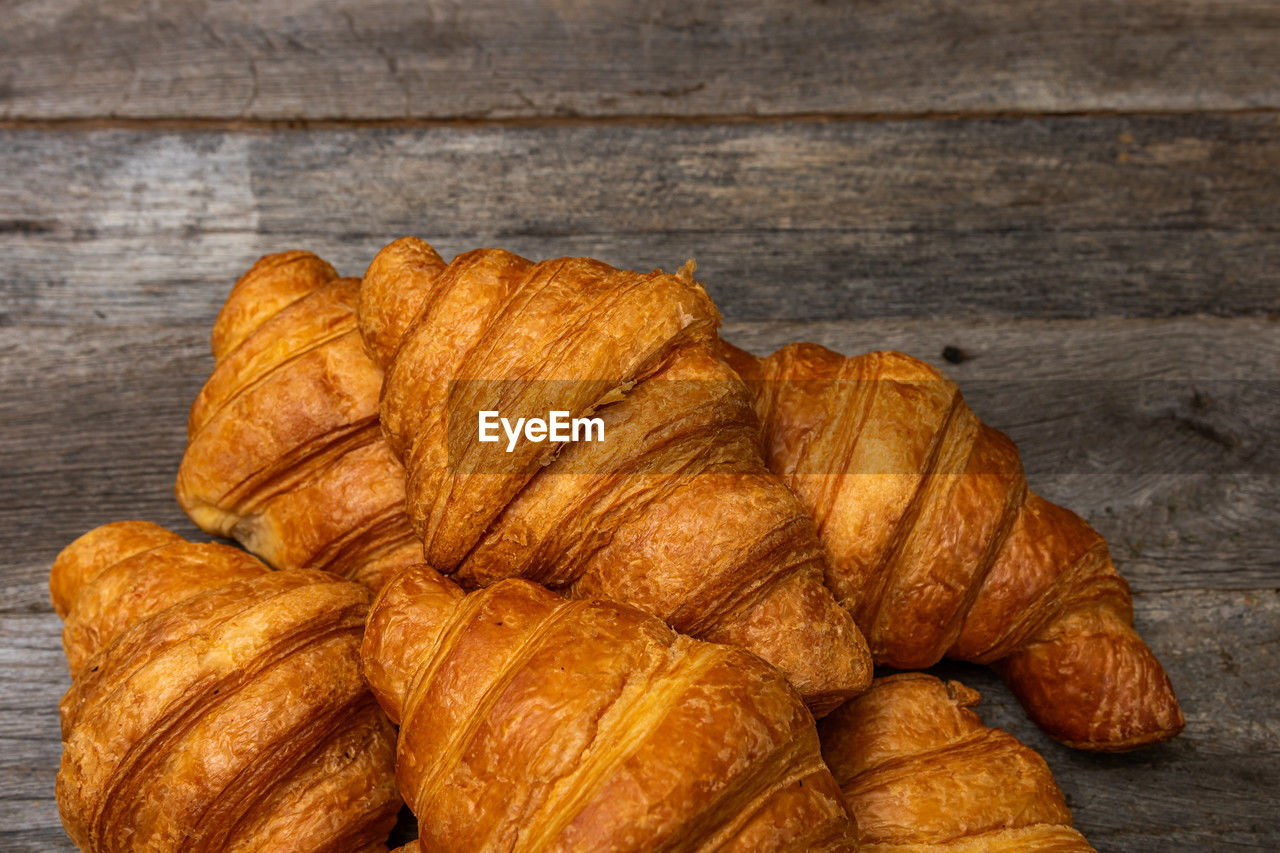 croissant, food and drink, food, french food, viennoiserie, baked, dessert, fast food, pastry, freshness, brown, still life, table, no people, bread, wood, close-up, high angle view, baked pastry item, indoors, loaf of bread, produce, bakery