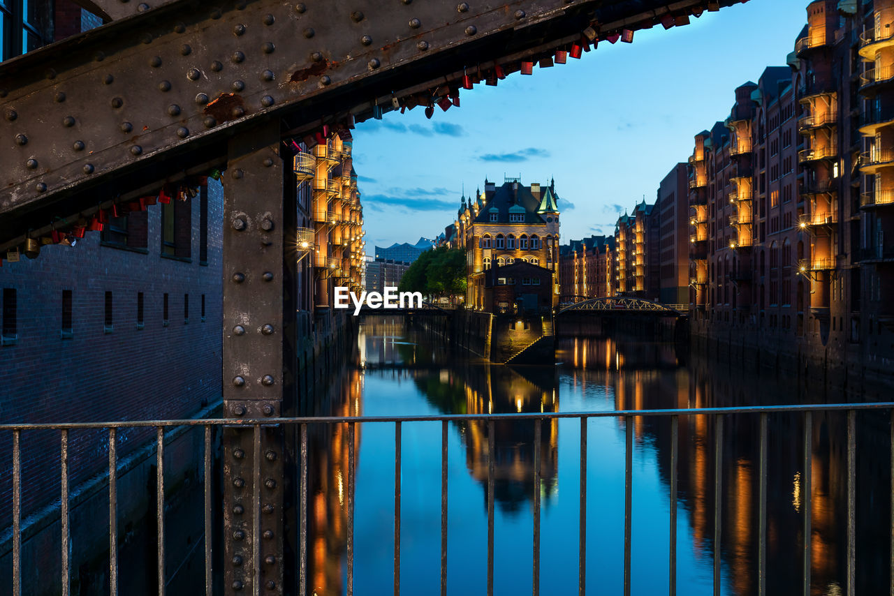 Bridge over river by buildings against sky in city
