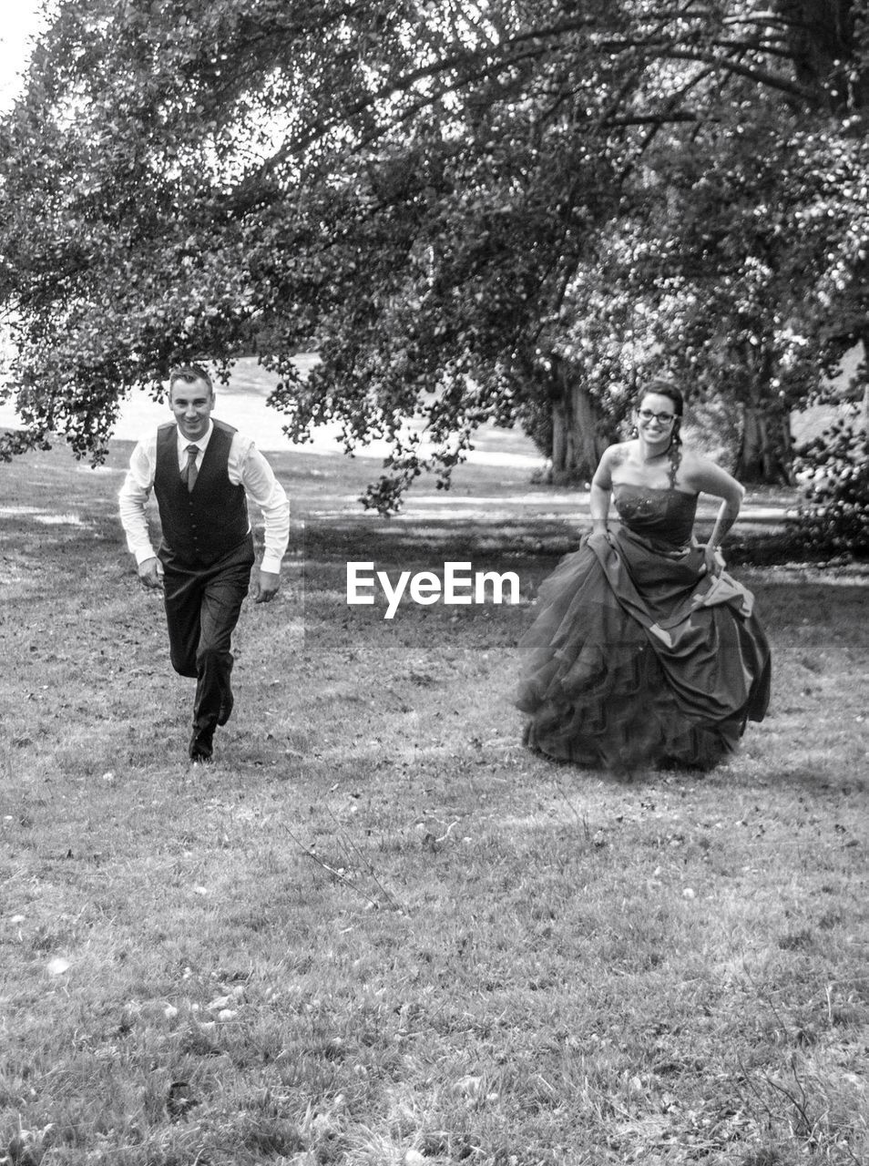 Portrait of bride and bridegroom walking on grassy field