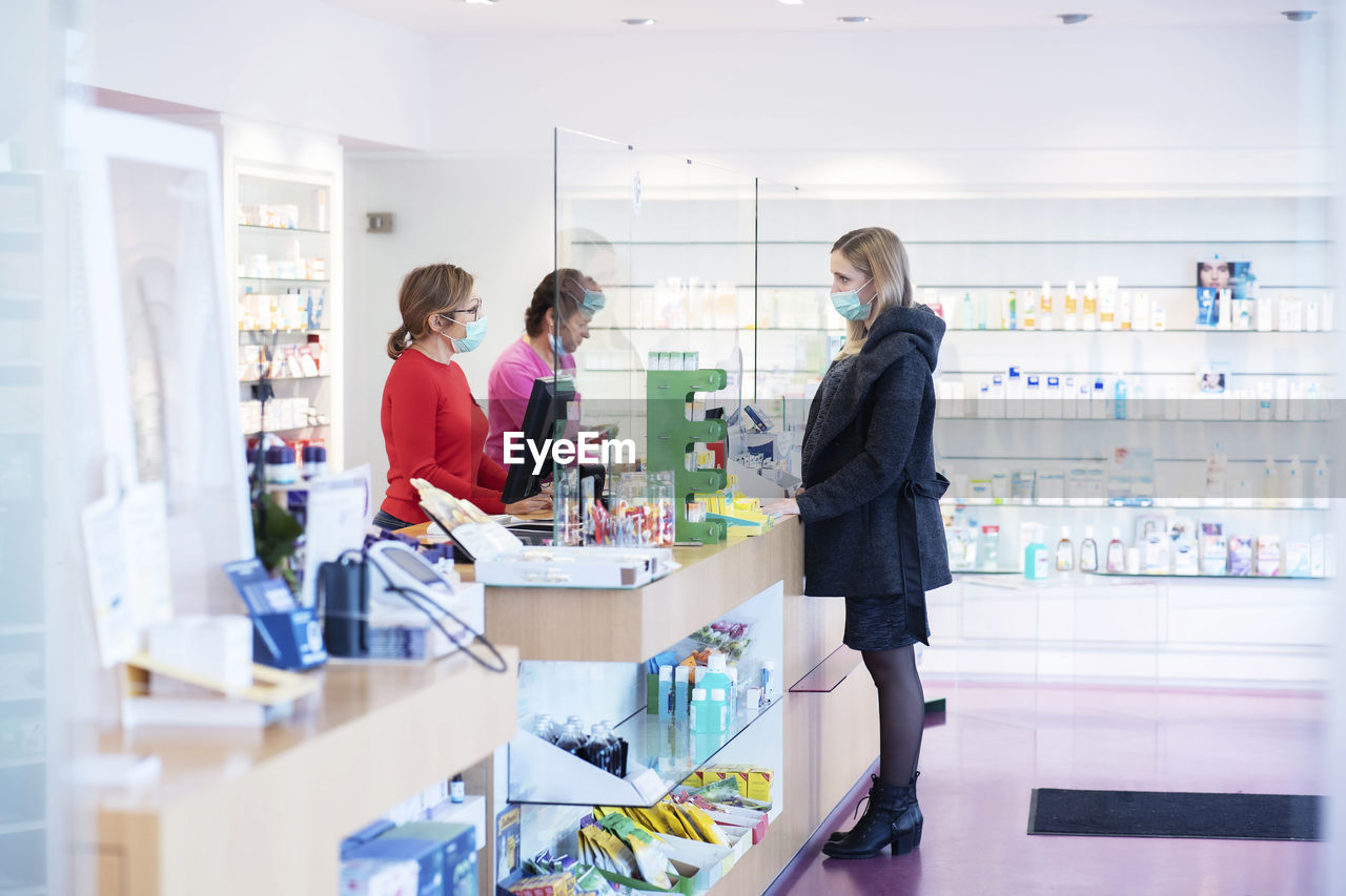 Pharmacist talking with customer at checkout counter of pharmacy store