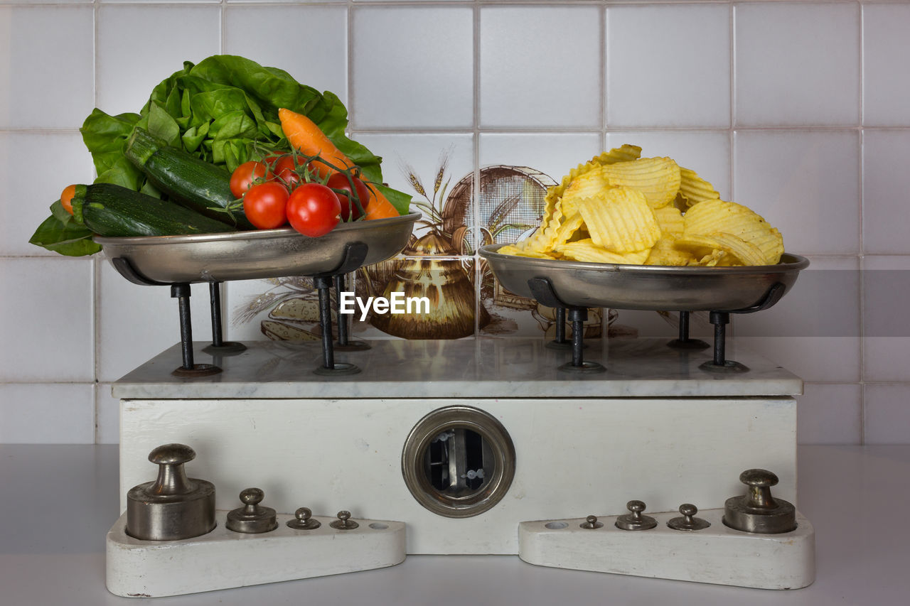 Close-up of potato chips and various vegetables on weight scale