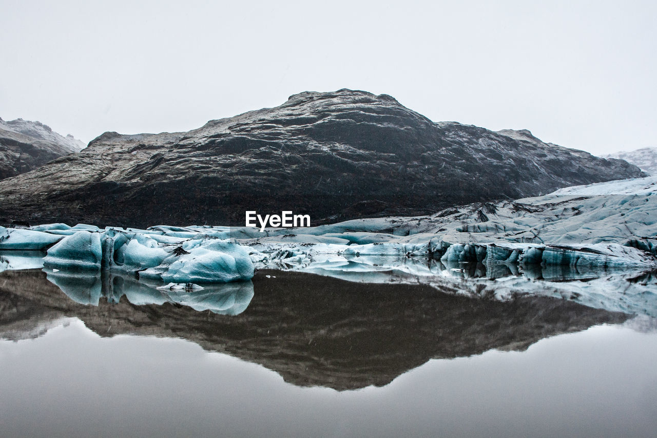 Scenic view of iceland glacier against mountain and sky during winter