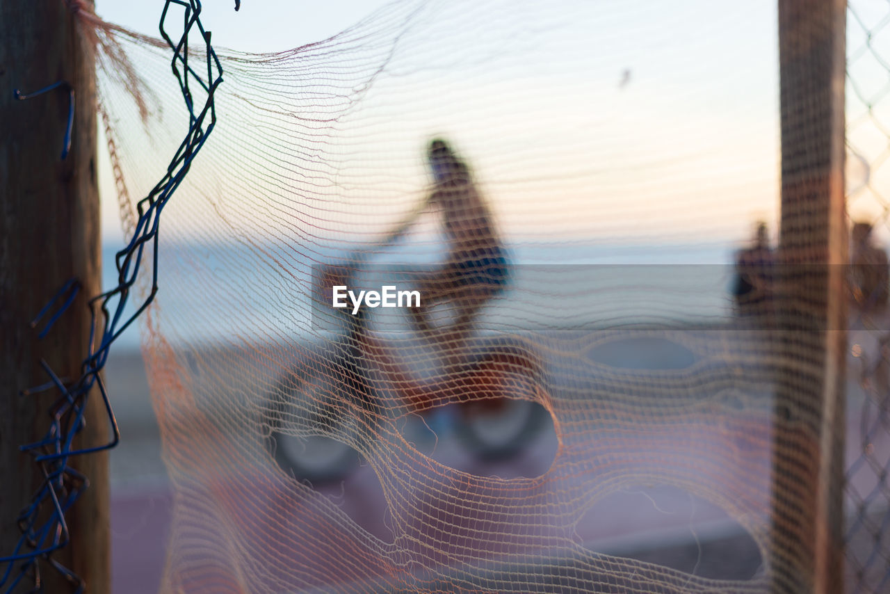 Silhouette of cyclists and people walking on the edge of a beach against sunset. 