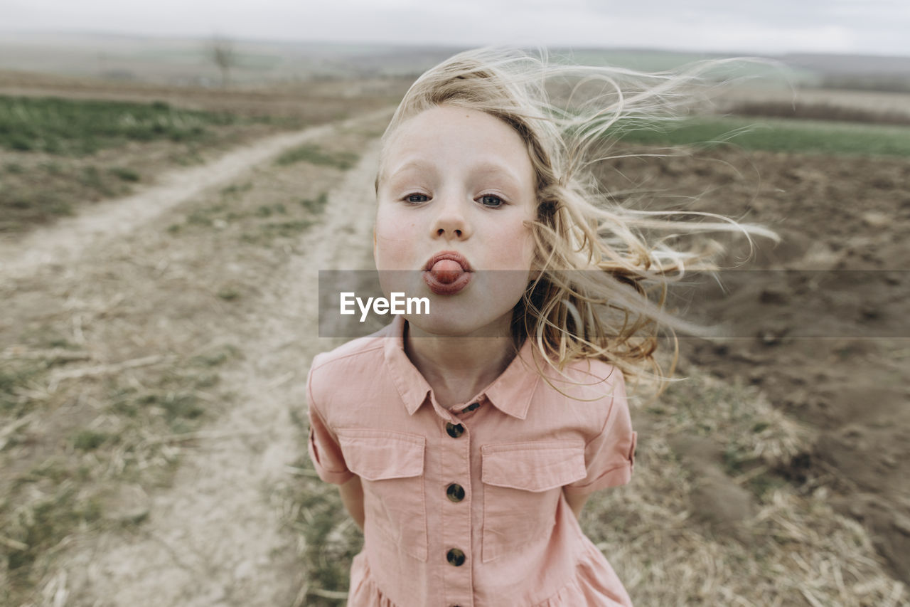 Girl sticking out tongue at agricultural field