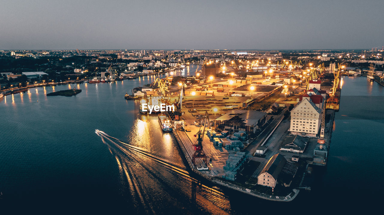 High angle view of illuminated cityscape by sea against sky