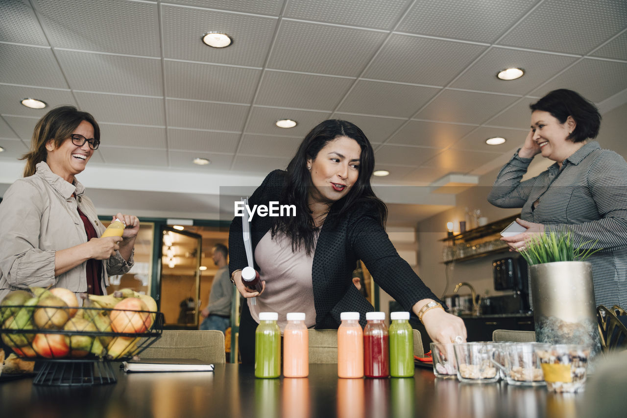 Smiling businesswoman taking food from table during conference event at office