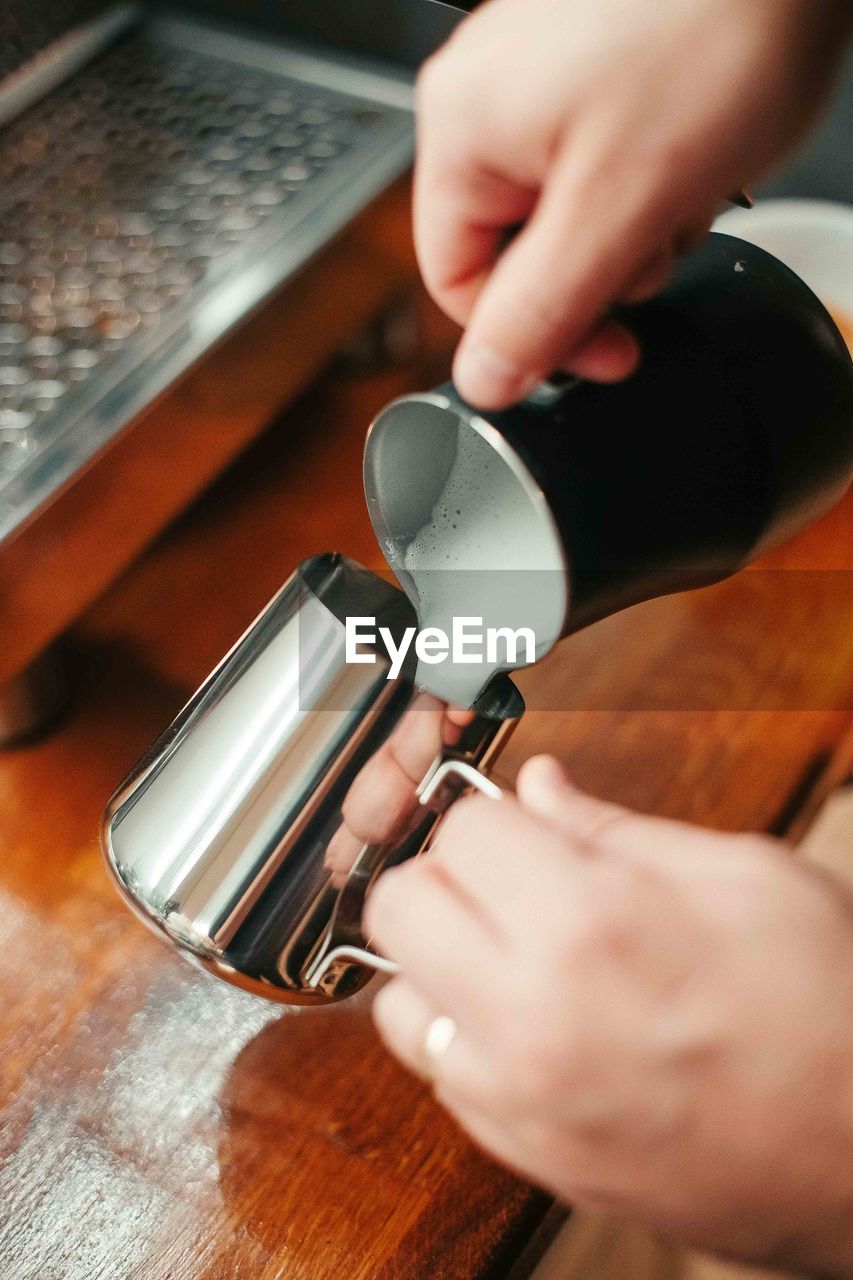 Cropped hands pouring milk in cup