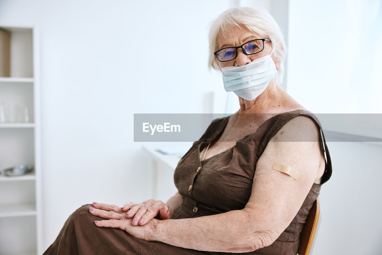 Portrait of senior woman wearing mask while sitting at hospital