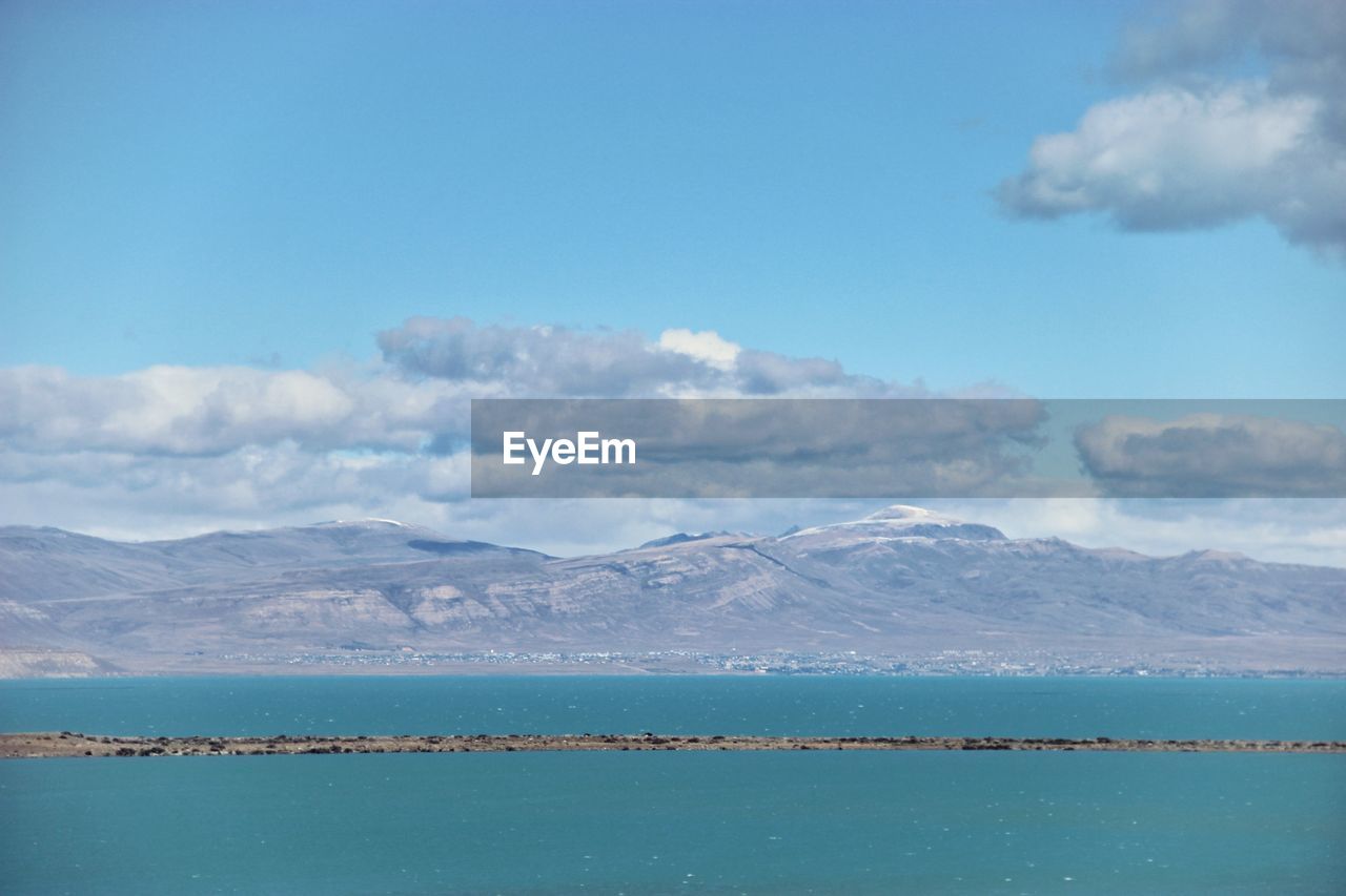 Scenic view of sea and mountains against blue sky