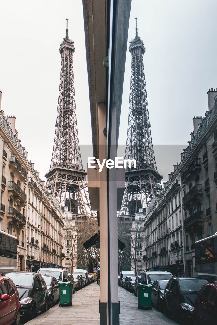 View of eiffel tower and building reflecting on window in city