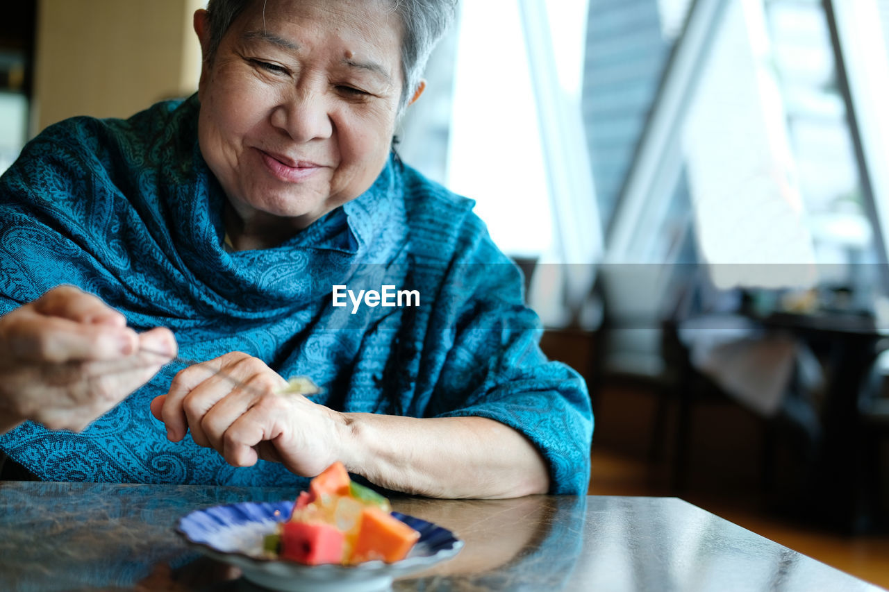 Senior woman eating breakfast at home