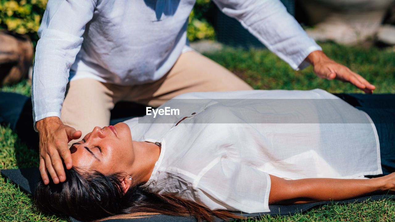 Close-up image of relaxed woman lying with her eyes closed and having reiki healing treatment 