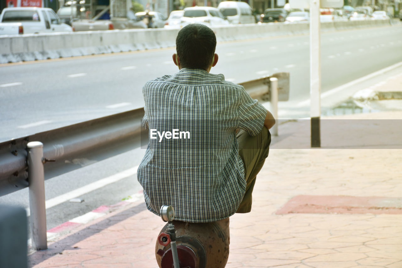 REAR VIEW OF MAN STANDING ON STREET