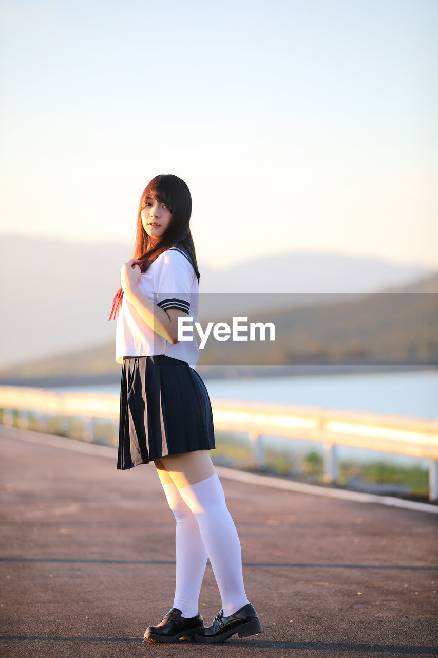 Full length of beautiful young woman wearing uniform while standing on road