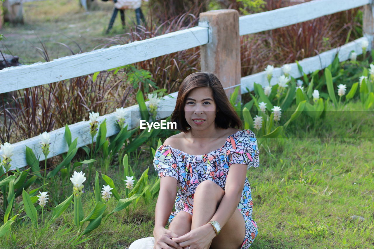 Portrait of smiling woman sitting on grassy field