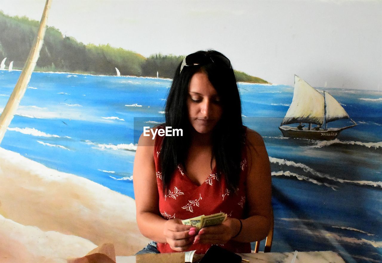 YOUNG WOMAN ON BEACH AGAINST SKY