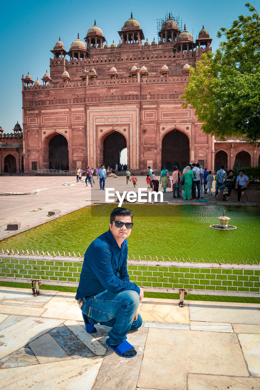 MAN SITTING ON STONE WALL