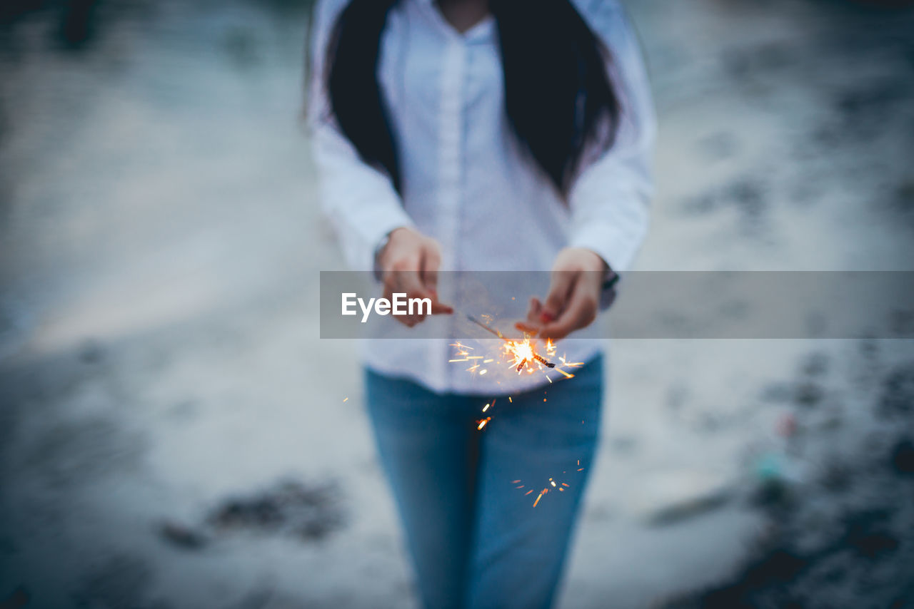 Midsection of woman holding sparkler