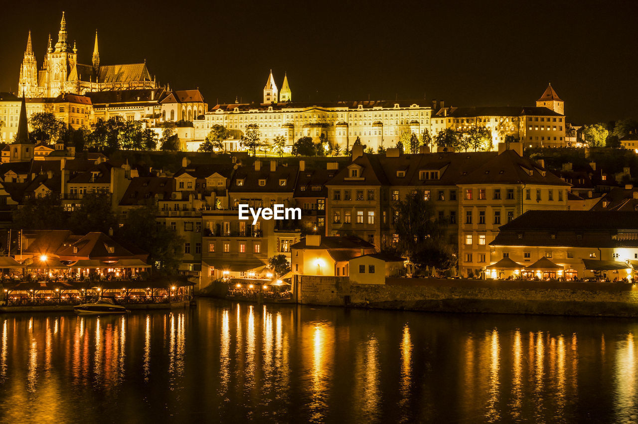 Illuminated cityscape by vltava river at night