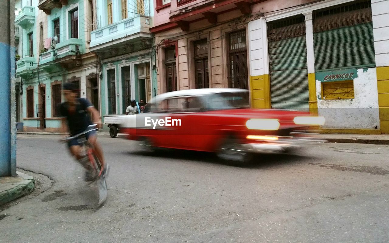 Blurred motion of car and man riding bicycle on street