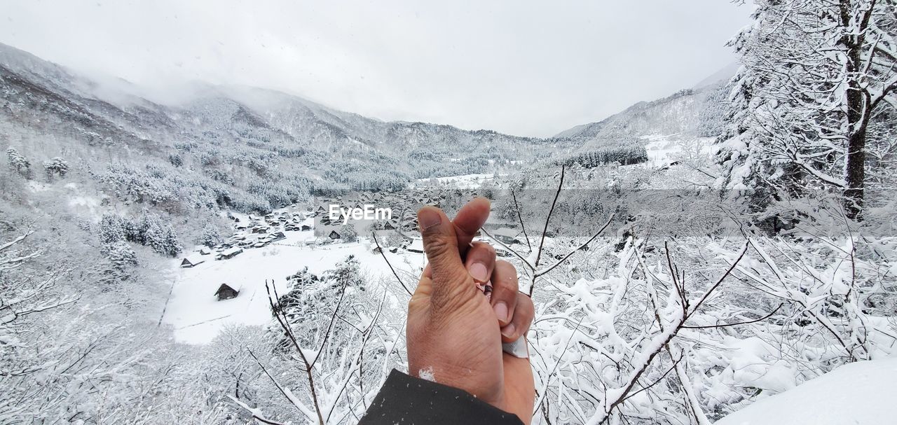 PERSON HAND ON SNOWCAPPED MOUNTAIN