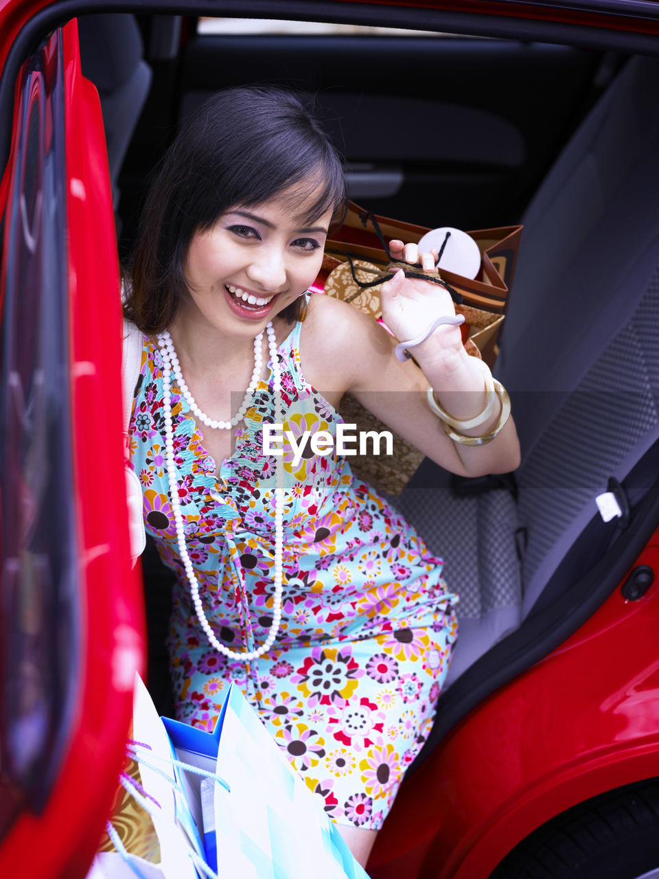 High angle portrait of young beautiful woman holding shopping bags while sitting in car
