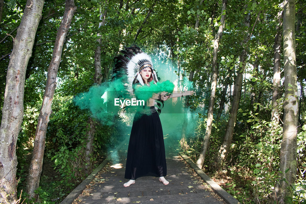 FULL LENGTH OF WOMAN STANDING BY TREES IN FOREST