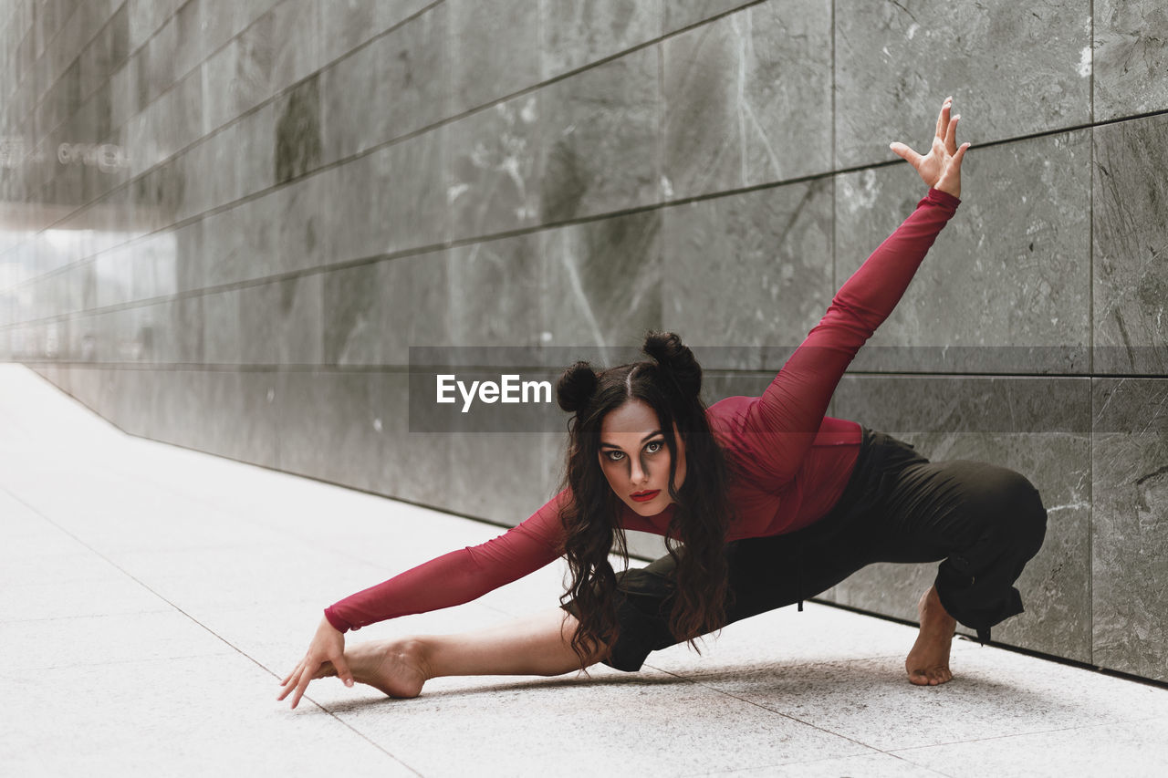 Full length of woman dancing on floor against wall